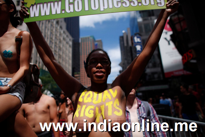 A woman holds a sign as she bares her naked chest in the GoTopless pride parade in Manhattan August 23, 2015 in New York City